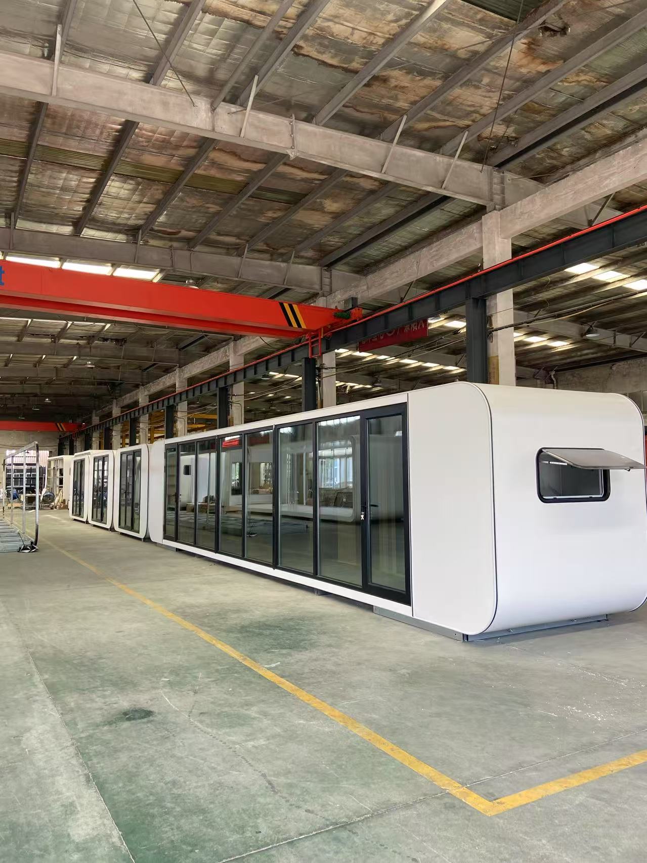 Cabina modular alargada de exterior blanco y grandes cristaleras dentro de un taller
