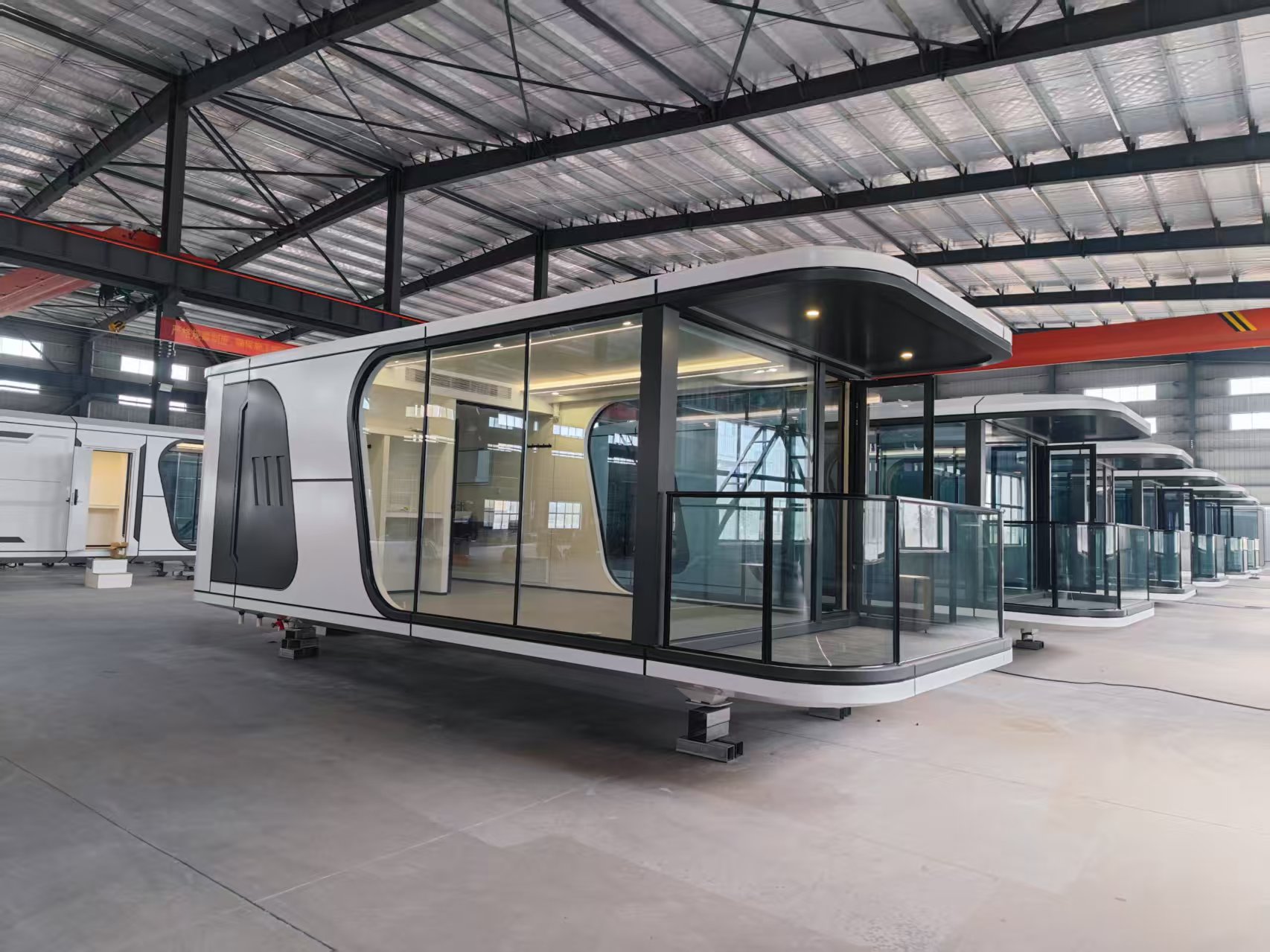Cabina modular blanca con terraza cubierta y barandilla de cristal en fábrica